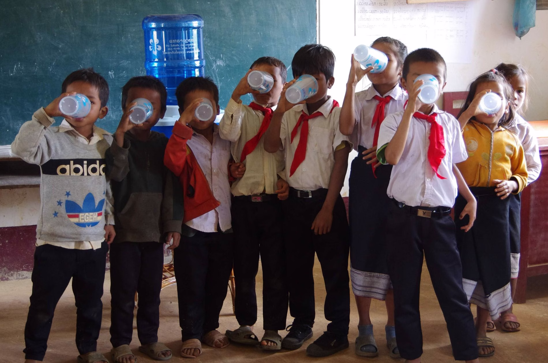 Schoolchildren drinking clean water from cups at a classroom water station